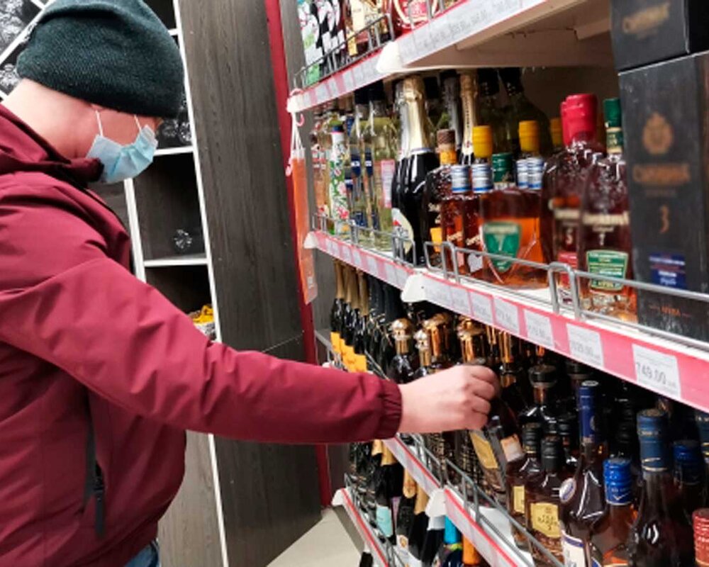 молодой человек покупает алкоголь